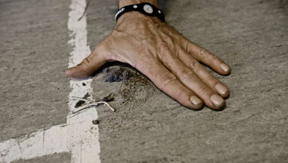 Hånd samler støv og jord på et gulv for at vise, at der er beskidt